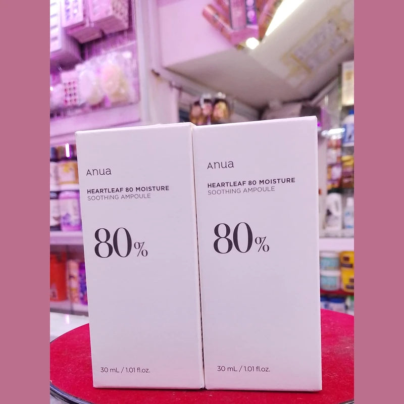 Two boxes of Anua Heartleaf 80 Moisture Soothing Ampoule on a red surface with a blurred store background.