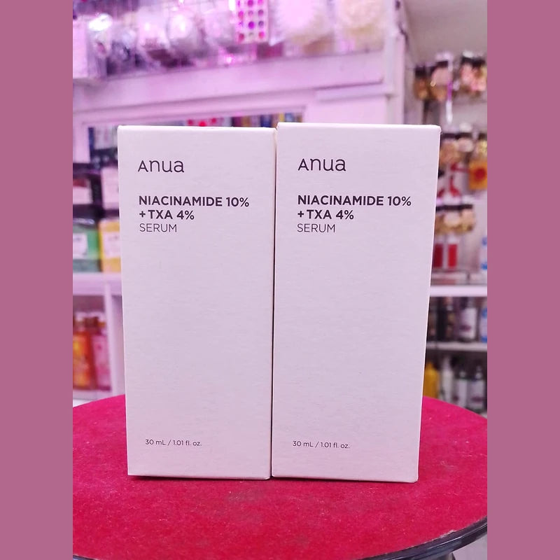 Two boxes of Anua Niacinamide 10% + TXA 4% Serum on a red surface with a blurred background.