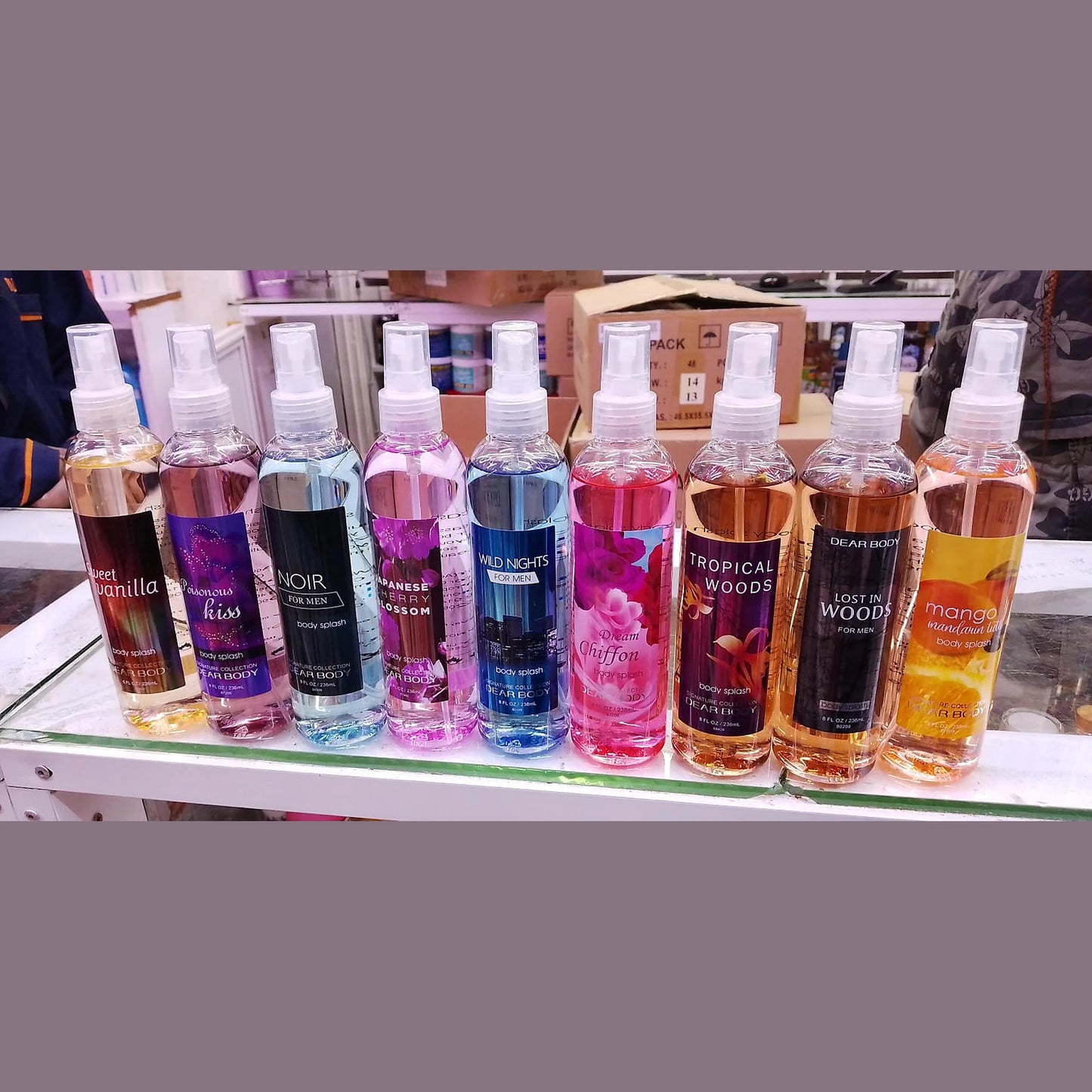 Row of spray bottles with various scents on a shelf.