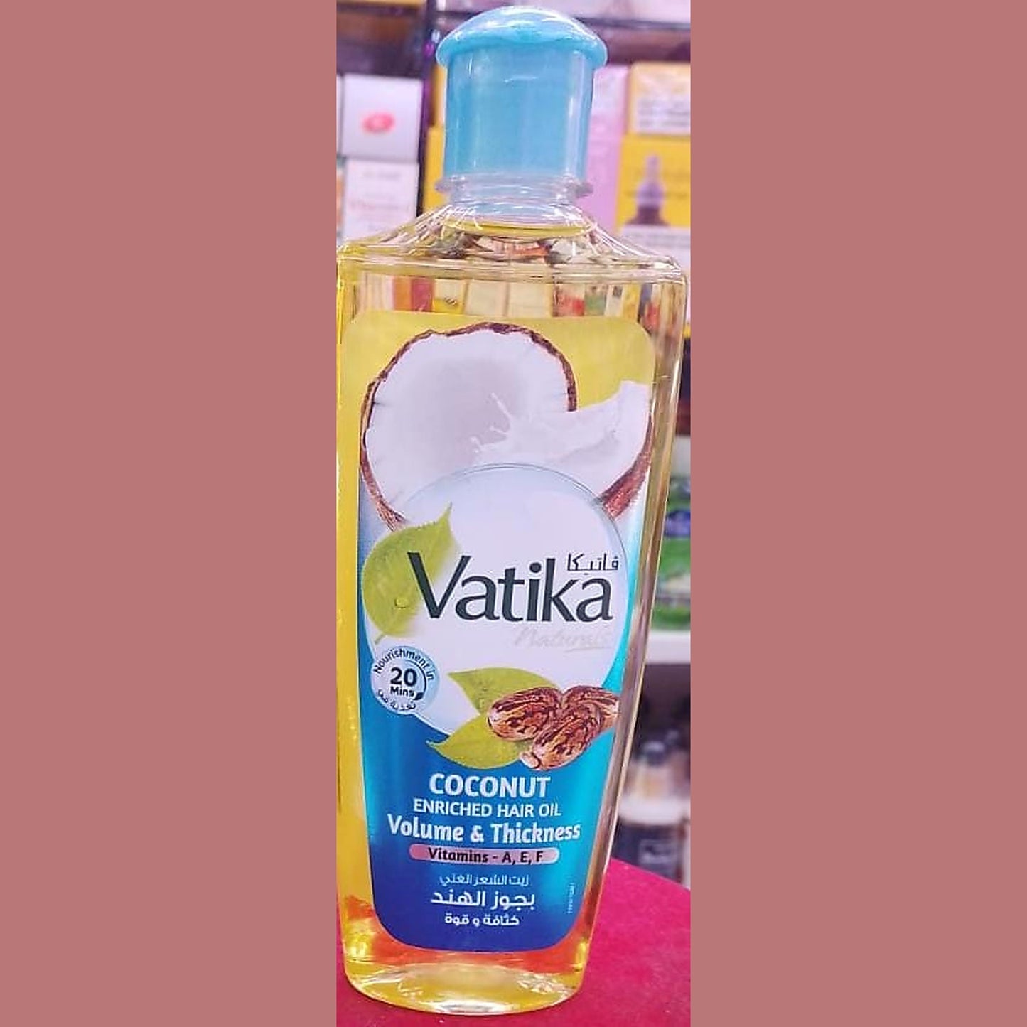 Vatika coconut enriched hair oil bottle on a red surface with a blurred background