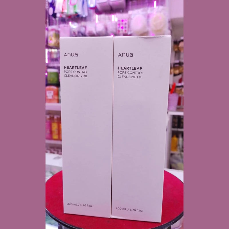 Two boxes of Anua Heartleaf Pore Control Cleansing Oil on a red surface with a blurred background.