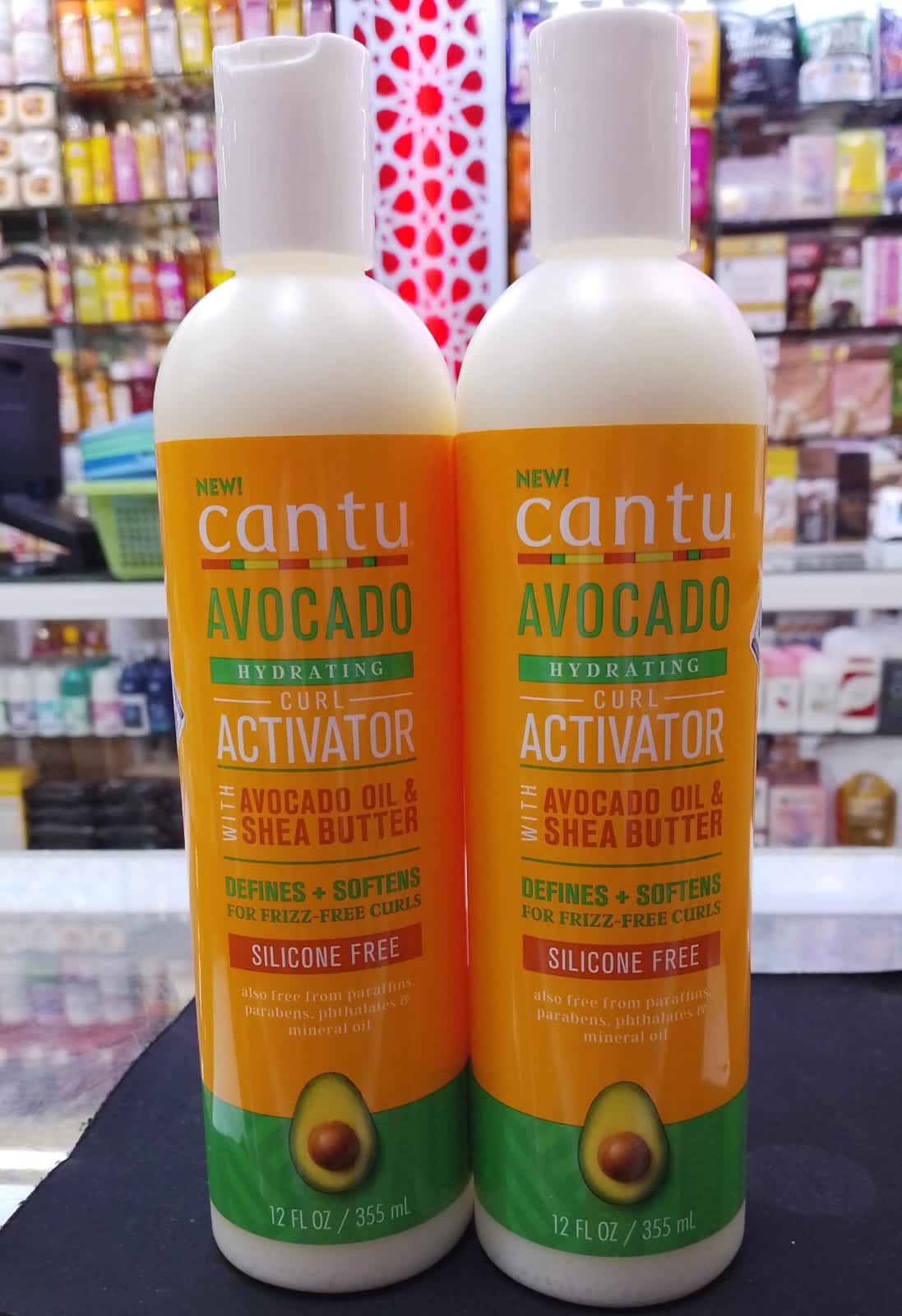 Two bottles of Cantu Avocado Curl Activator on a shelf with products in the background.