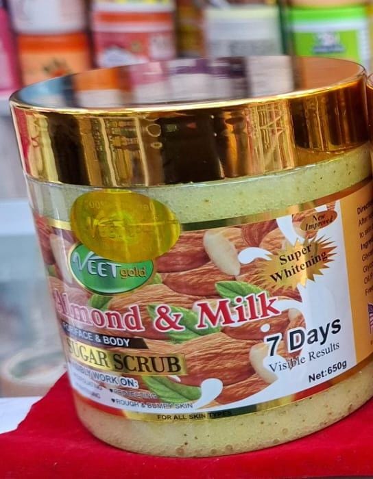 Jar of almond and milk sugar scrub with gold lid on a red surface