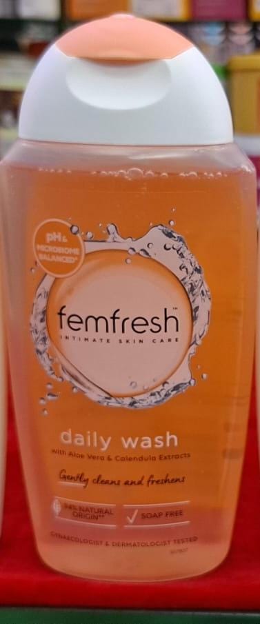 Femfresh daily wash bottle on a green surface with a blurred background