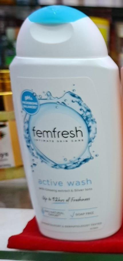 Femfresh active wash bottle on a red surface with a blurred background