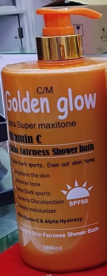 Orange and gold bottle of Golden Glow shower bath with text on a red surface