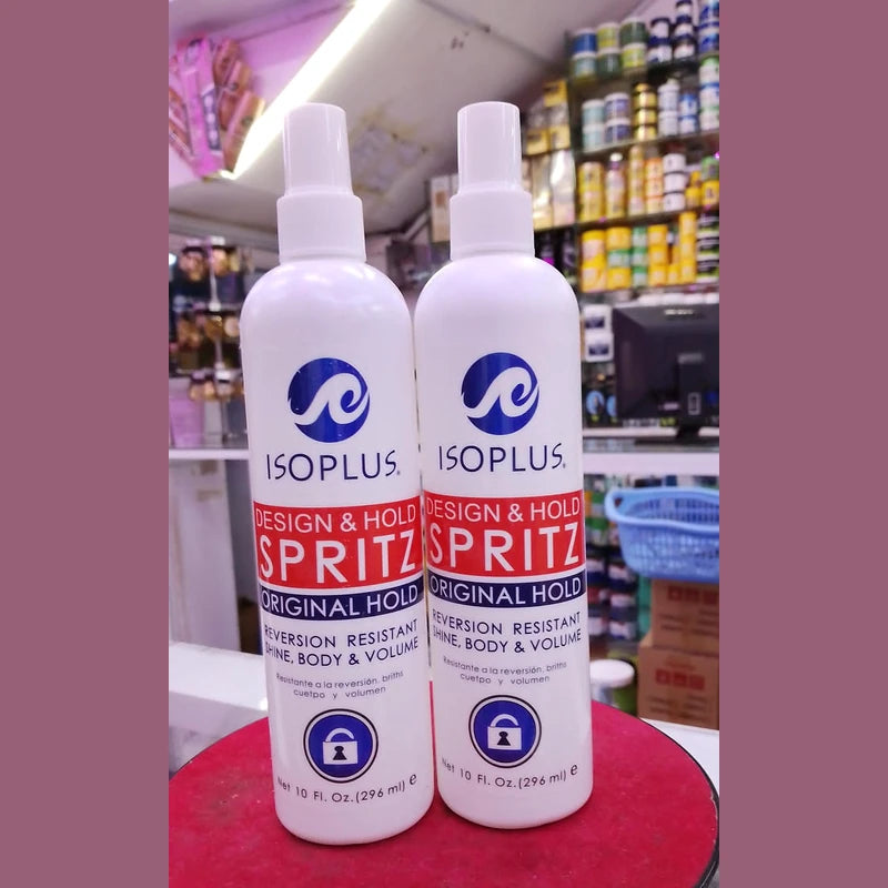 Two bottles of ISOPLUS Design & Hold Spritz on a red surface with a store shelf in the background.