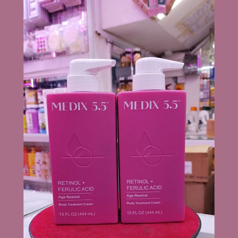 Two pink bottles of Medix 5.5 skincare product on a red surface with a blurred store background.
