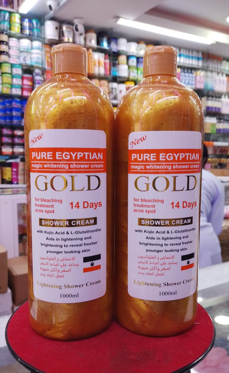 Two bottles of Pure Egyptian Gold shower cream on a red surface with a store shelf in the background.