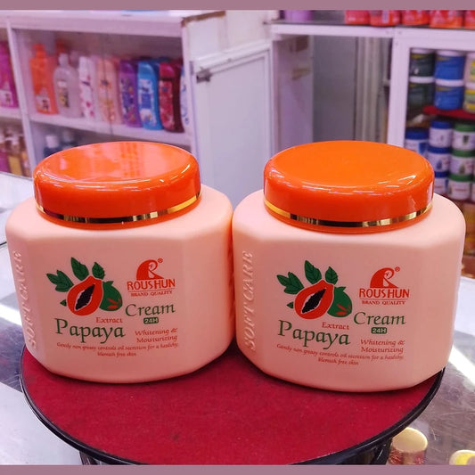 Two jars of Papaya Extract Cream by Roushun on a red surface with a blurred store background.