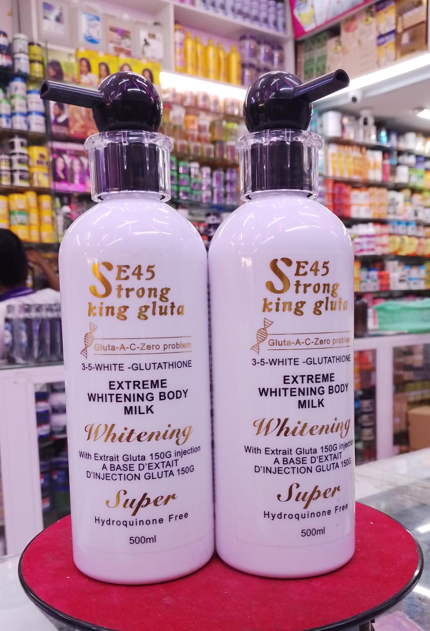 Two bottles of 'Strong King Gluta' whitening body milk on a red surface with a store shelf in the background.