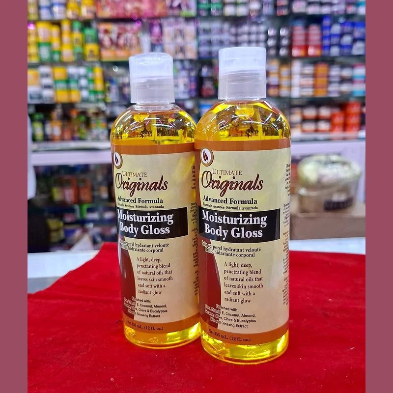 Two bottles of 'Ultimate Originals' moisturizing body gloss on a red surface with a store shelf in the background.