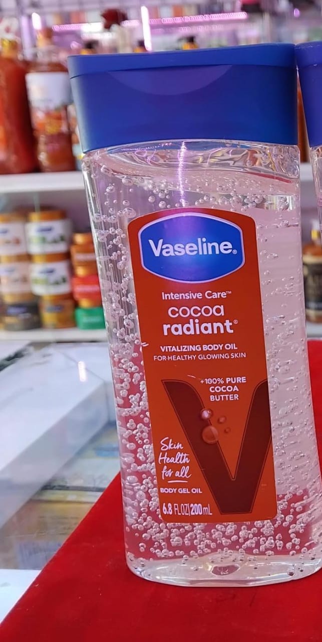 Vaseline Intensive Care Cocoa Radiant body oil bottle on a red surface with blurred background