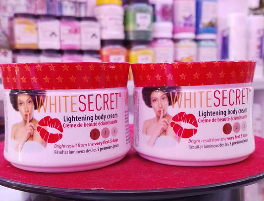 Two jars of White Secret lightening body cream on a red surface with blurred background.