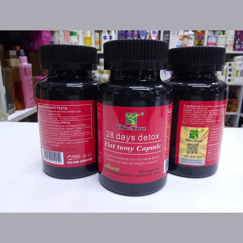 Three bottles of '28 days detox Flat tumy Capsule' on a white surface with a blurred background.