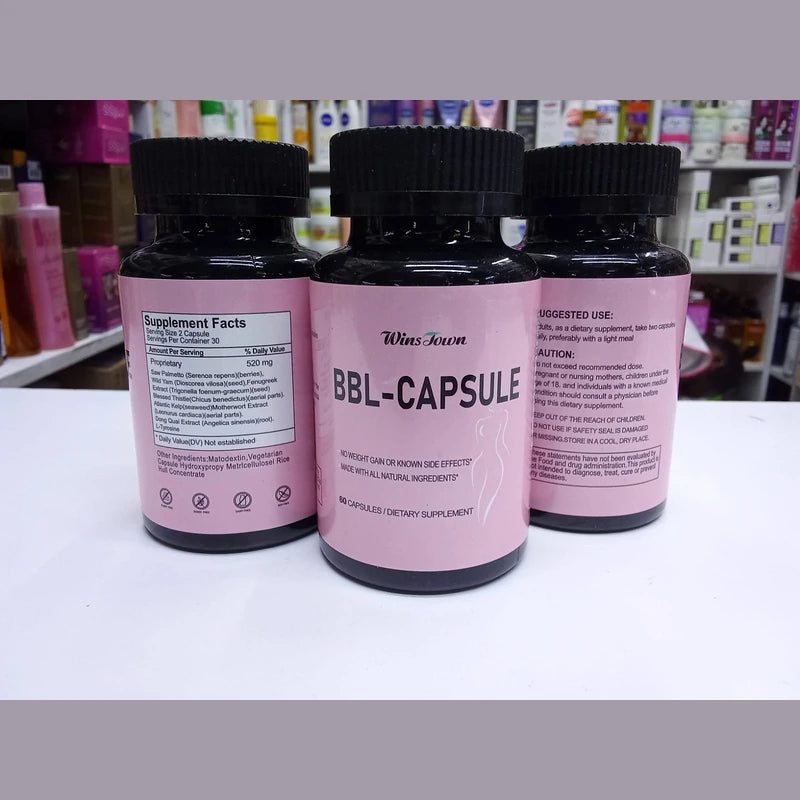 Three pink supplement bottles labeled 'BBL-CAPSULE' on a white surface with a blurred store background.