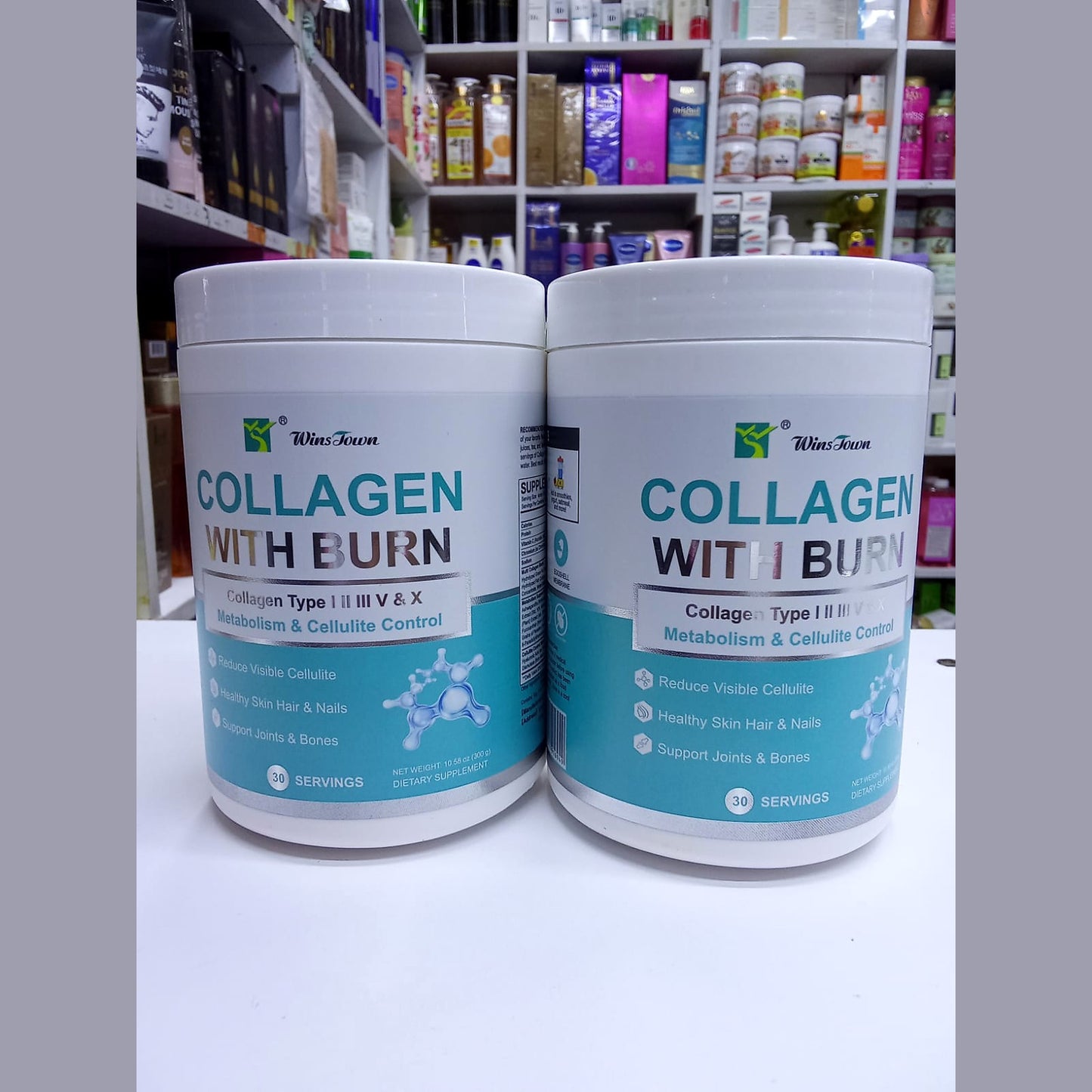 Two containers of 'Collagen with Burn' supplement on a white surface with a blurred store shelf in the background.