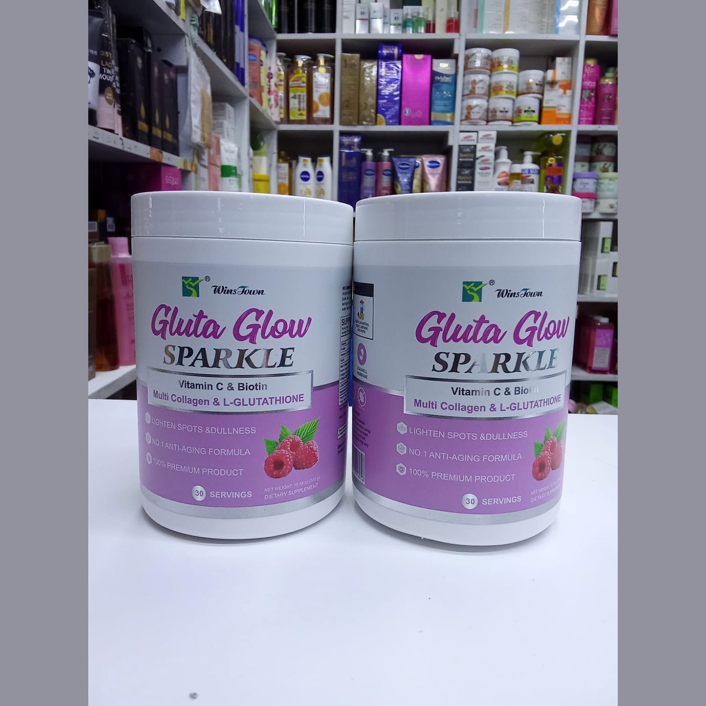 Two containers of 'Gluta Glow Sparkle' product on a shelf with various other products in the background.