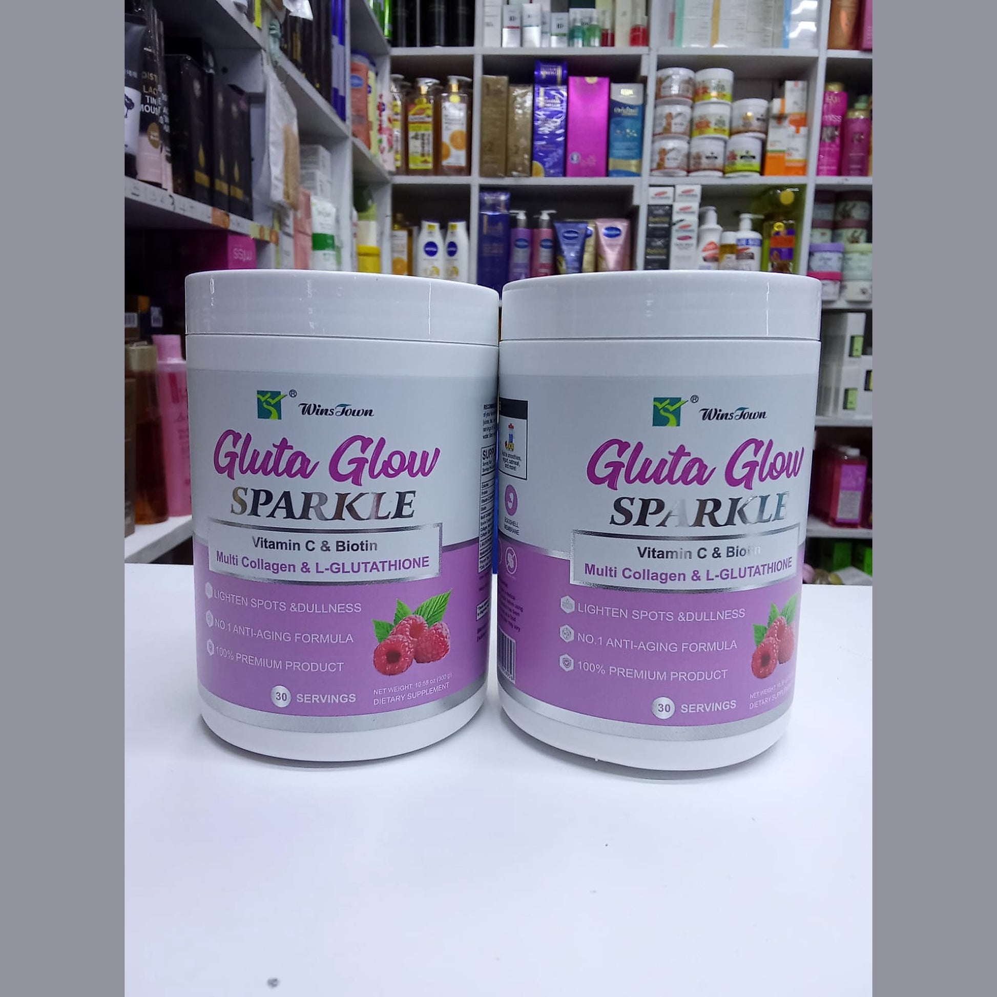 Two containers of 'Gluta Glow Sparkle' product on a shelf with various other products in the background.